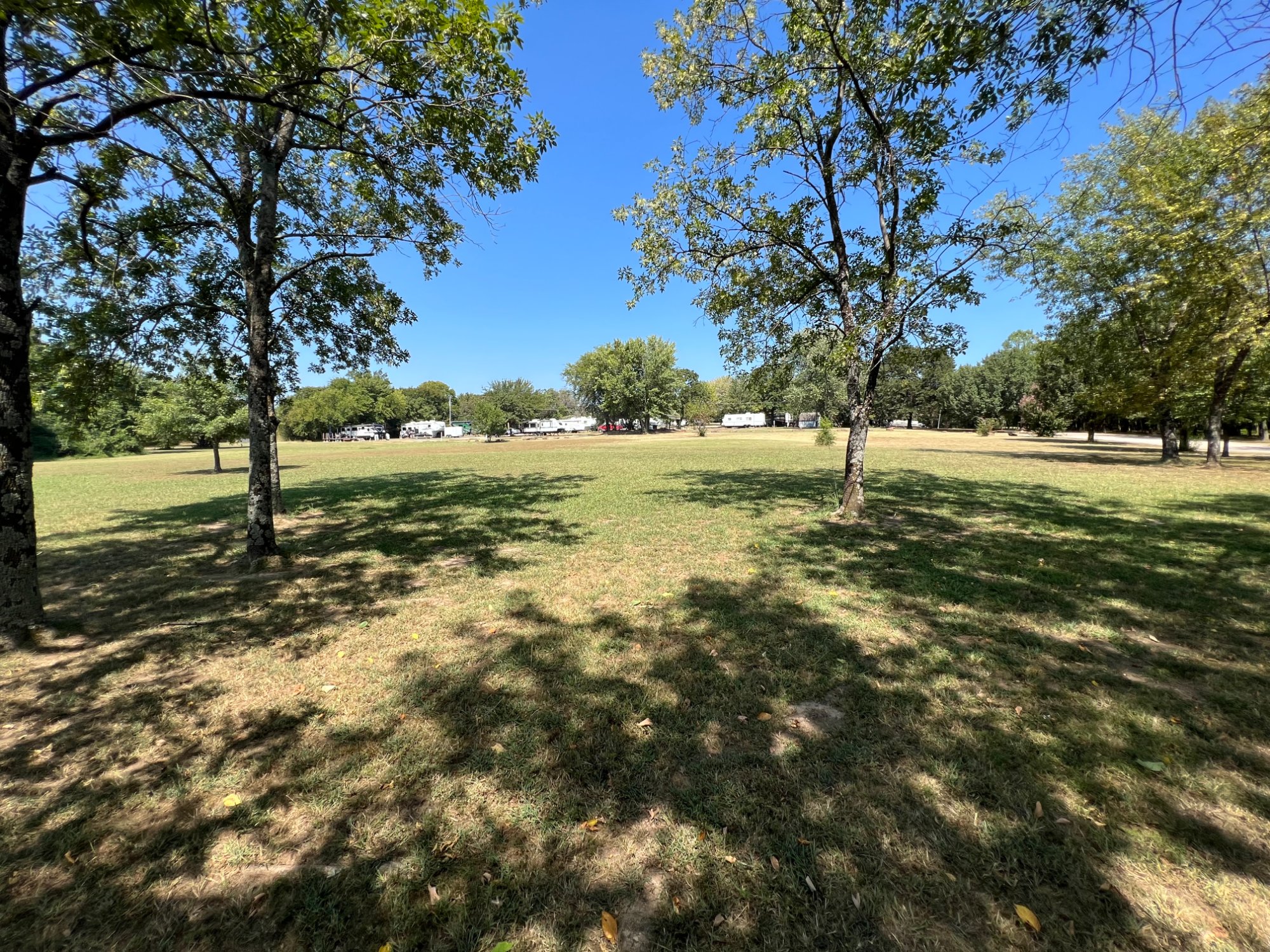 Open manicured lawn with shade trees at Gibson RV Park near Fort Gibson Lake
