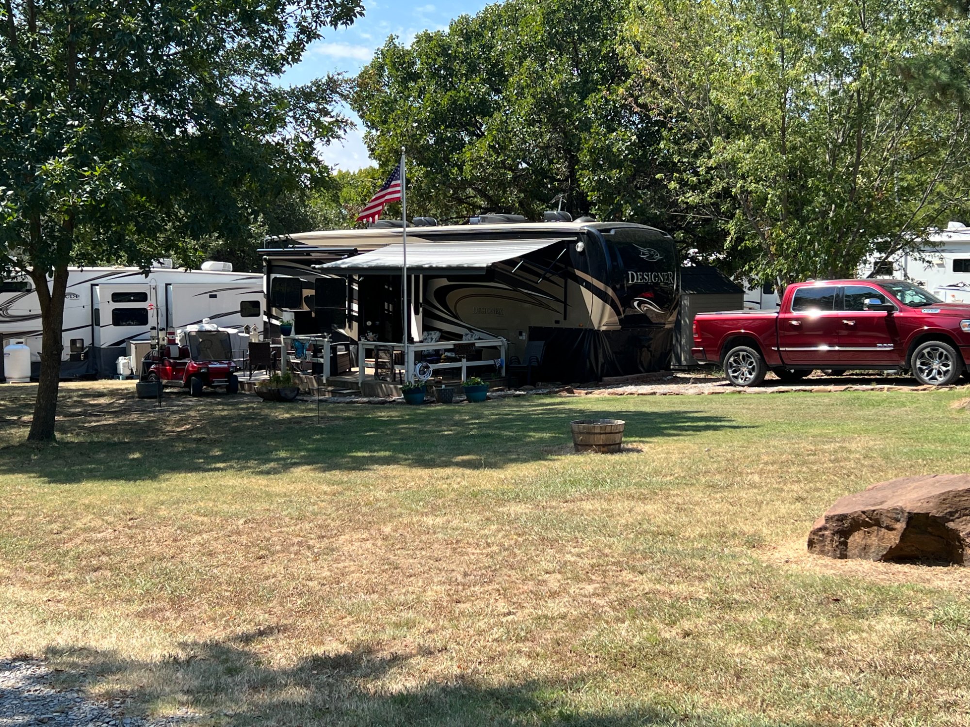 Shaded fifth wheel RV site with American flag at Gibson RV Park Wagoner Oklahoma