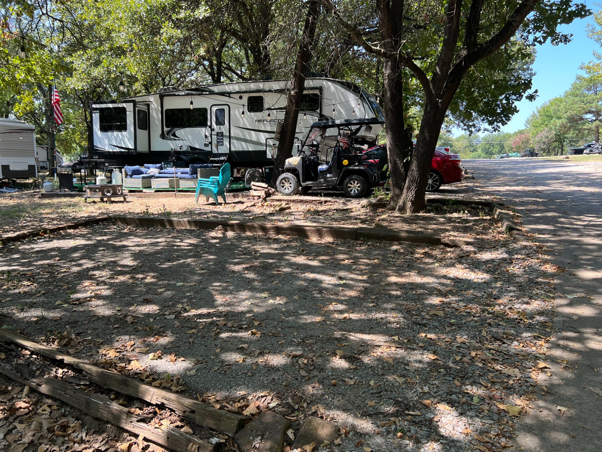 Reflection travel trailer at shaded site with UTV and string lights
